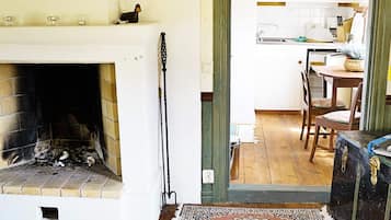 A room with a fireplace, a dining area with chairs, a kitchen with cabinets, and a rug on the floor.