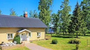 A single-story house with a porch, a small deck, and a gravel driveway. - Holiday Home in Hova (Hova)