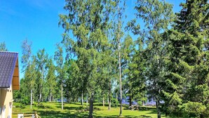 A wooden deck with outdoor furniture, surrounded by a grassy area and trees. - Holiday Home in Hova (Hova)