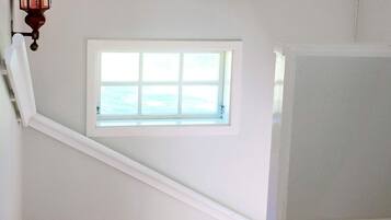 A staircase with a small window, white walls, and a wooden floor.