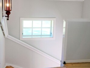 A staircase with a small window, white walls, and a wooden floor. - Holiday Home in Hova (Hova)