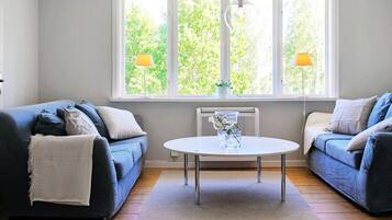 Een moderne woonkamer met twee banken, een ronde tafel en een groot raam met uitzicht op groen.