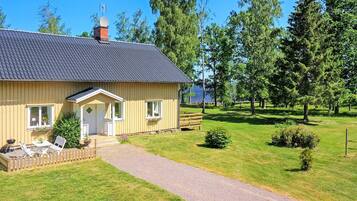 Ett envåningshus med en veranda, en liten terrass och en grusuppfart.