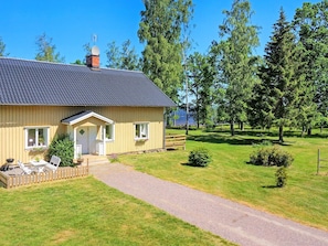 A single-story house with a porch, a small deck, and a gravel driveway. - Holiday Home in Hova (Hova)