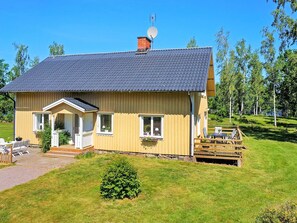 A single-story wooden house with a sloped roof, a satellite dish, and a small porch with outdoor seating. - Holiday Home in Hova (Hova)