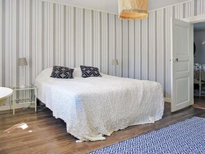 A bedroom with a bed, two bedside lamps, a striped wall, and a patterned rug. - Holiday Home in Hova (Hova)
