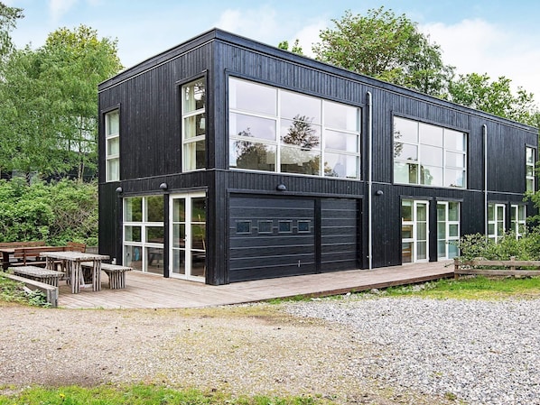 A modern two-story building with large windows and a garage.