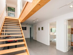 Un intérieur moderne avec un escalier en bois, un jeu de fléchettes et un baby-foot.