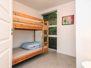 Una cama litera con escalera, una ventana con vistas a la vegetación y un cuadro en la pared.