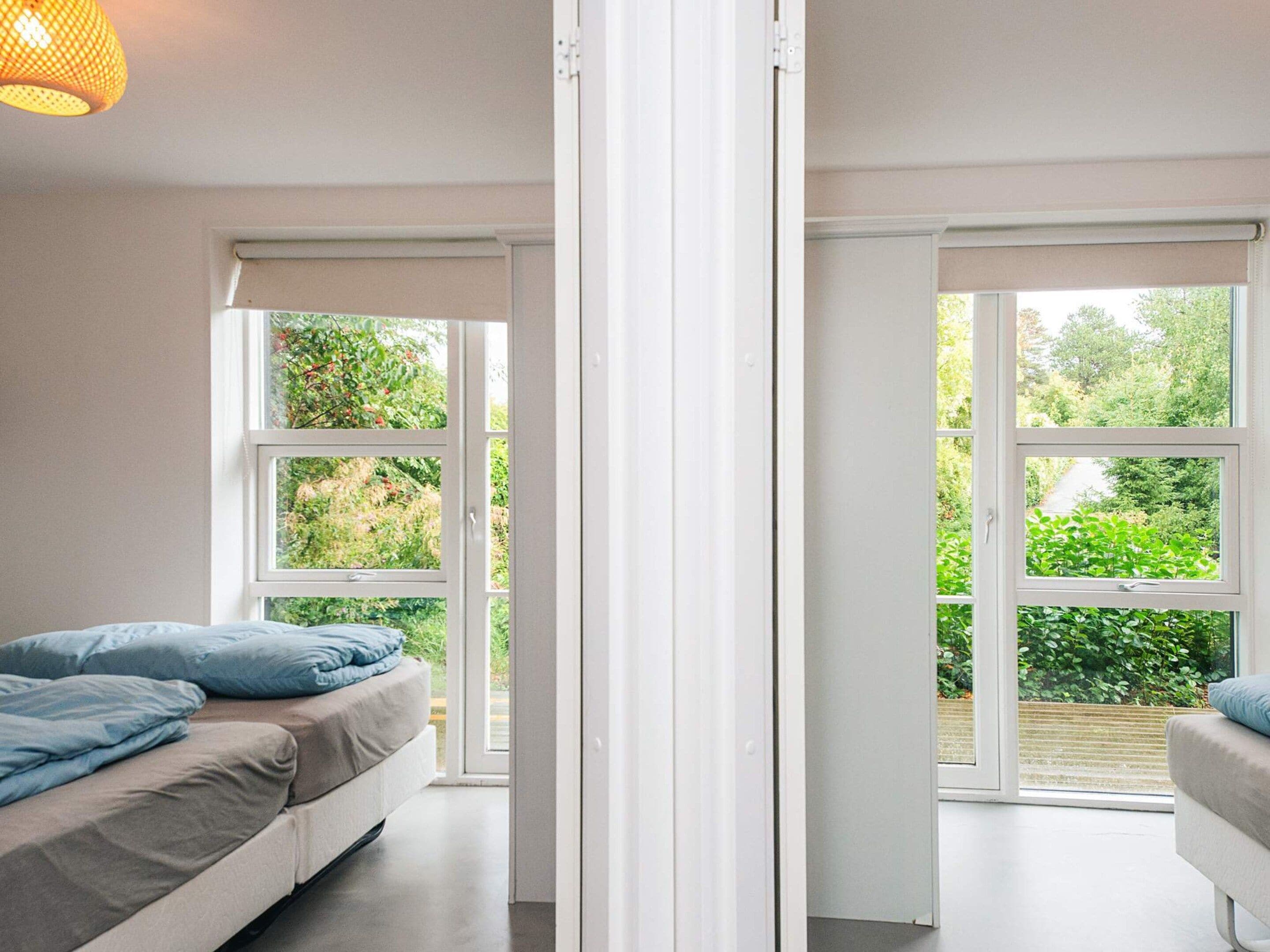 A bedroom with a bed, a window, and a view of greenery outside.