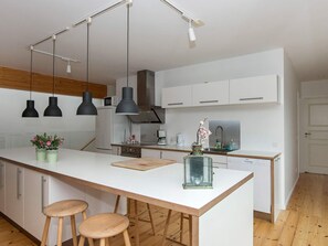 A modern kitchen with a central island, pendant lights, and bar stools.