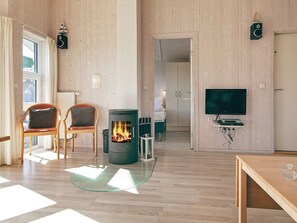 A modern living room with a fireplace, wooden flooring, a TV, and a glass coffee table.