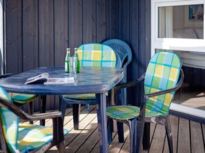 A round glass table with two chairs, each with a checkered cushion, and two bottles of water on the table.