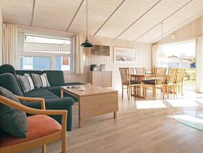 Un salon moderne comprenant un canapé, des fauteuils, une table basse et un coin repas avec une table et des chaises.