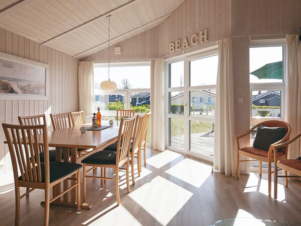 A dining area with a wooden table and chairs, a view of the outside, and a sign that reads 'BEACH'.
