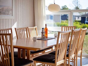 A dining area with a wooden table and chairs, a bottle of liquor, and a decorative item on the table. - Holiday Home in GrÃ¶mmitz (Groemitz)