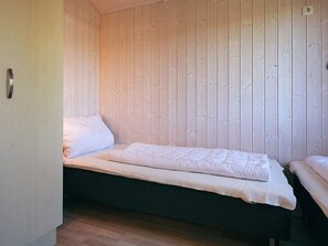 A single bed with a dark frame and white bedding in a room with wooden panel walls. - Holiday Home in GrÃ¶mmitz (Groemitz)