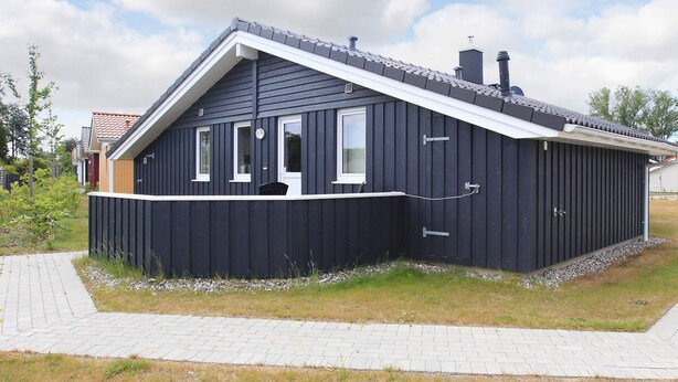 A single-story building with a dark exterior, a pitched roof, and a small porch area.