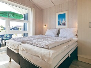 A bedroom with a bed, a window, and a painting on the wall.
