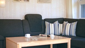 A modern living room with a dark grey sofa, striped pillows, a wooden coffee table, and a white cup.
