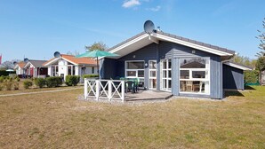 A residential property with a covered patio, satellite dishes, and a well-maintained lawn.