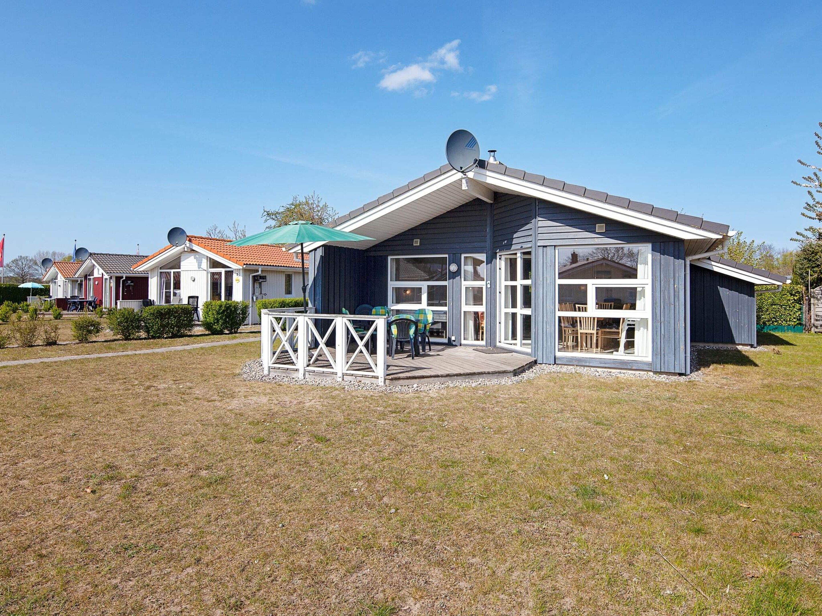 A residential property with a covered patio, satellite dishes, and a well-maintained lawn.