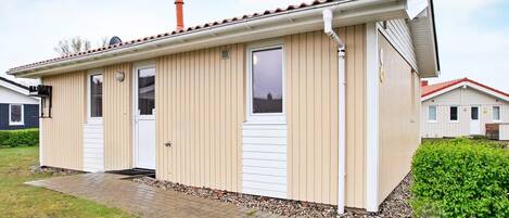 A single-story building with a tiled roof, two doors, and a small window.