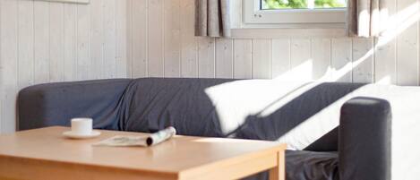 Une pièce avec une table en bois, un canapé gris et une fenêtre avec des rideaux.