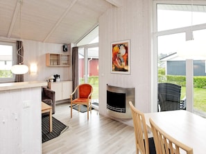 A modern living room with a fireplace, a dining area, and a view of the outdoors. - Holiday Home in GrÃ¶mmitz (Groemitz)