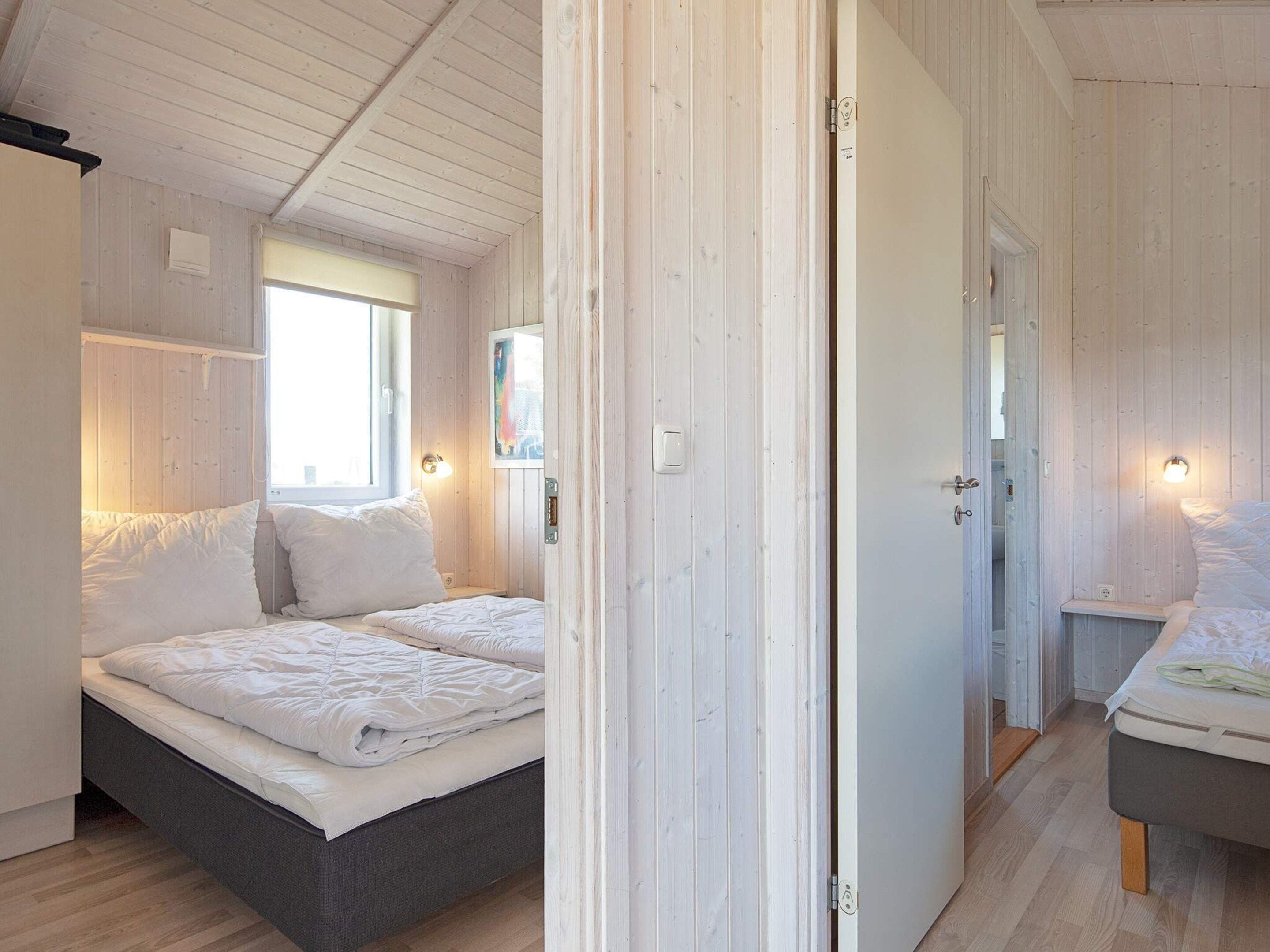 A bedroom with a bed, bedside tables, and a window.