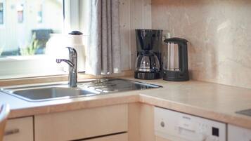 A kitchen with a sink, a coffee maker, and a dishwasher.