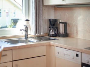 Una cocina con un lavaplatos, una cafetera y un fregadero.