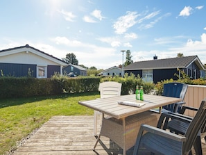 A wooden deck with a table and chairs, surrounded by a well-maintained lawn and hedges. - Holiday Home in GrÃ¶mmitz (Groemitz)