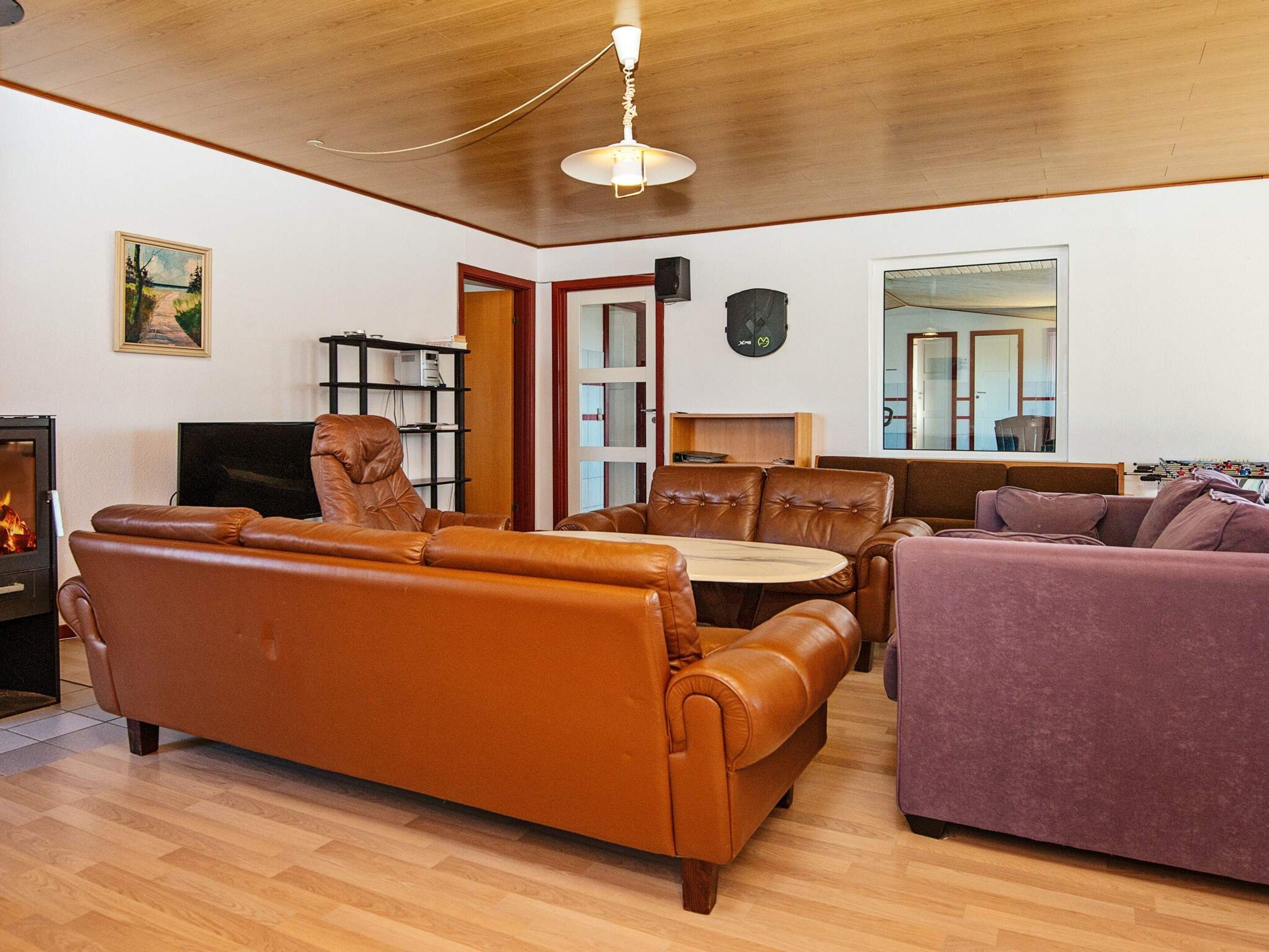 Una sala de estar con chimenea, sofás de cuero, una mesa de comedor y un televisor.