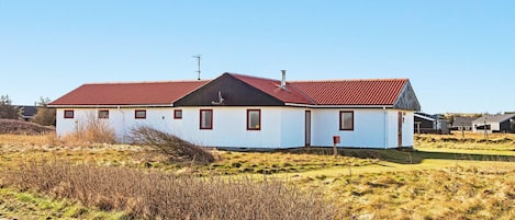 A single-story building with a red roof, white walls, and a small porch area.