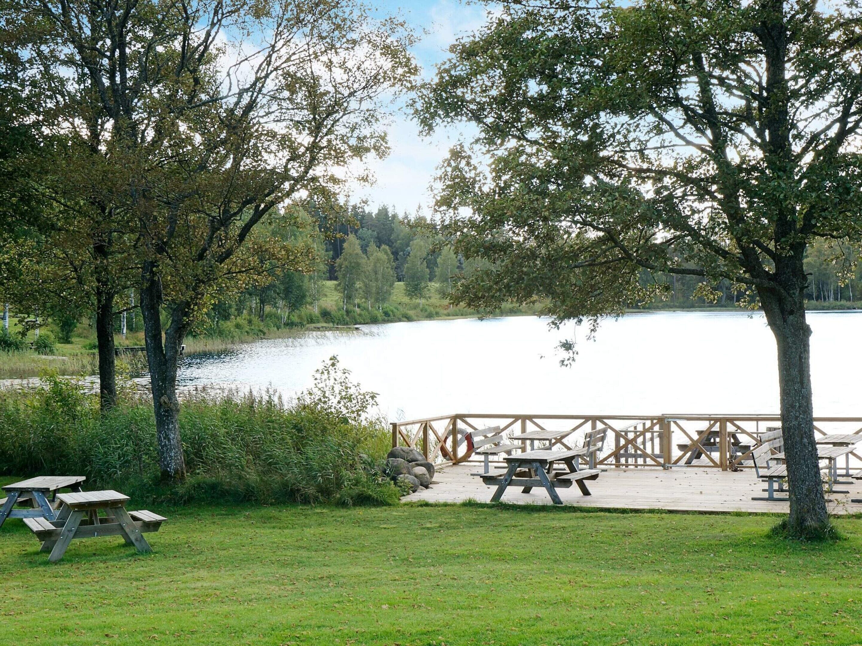 En picknickplats vid sjön med träbänkar och picknickbord.