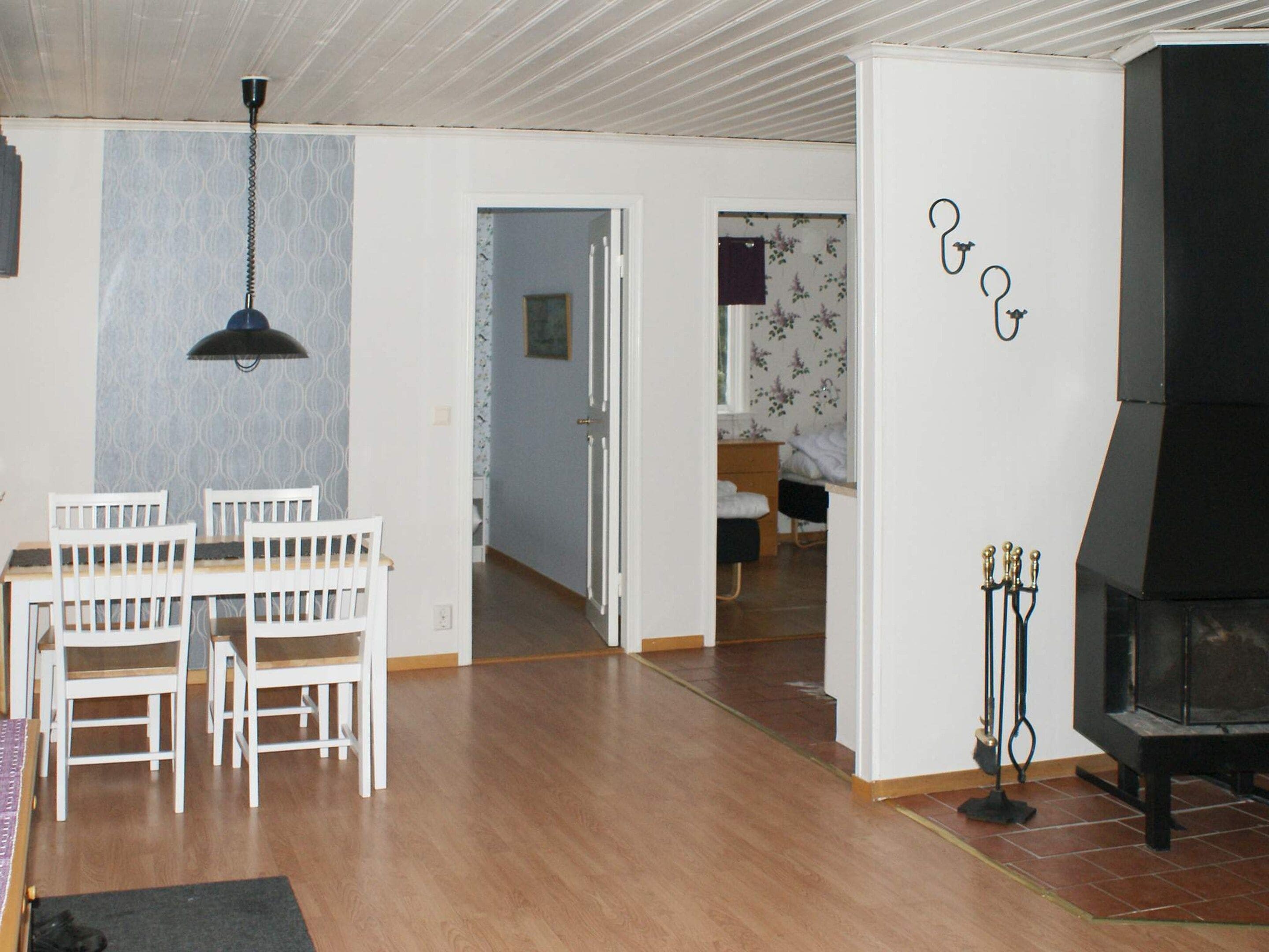 A dining area with a table and chairs, a hanging light fixture, and a fireplace.