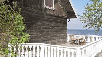 A wooden cabin with a white balcony, a window, and a view of the sea.