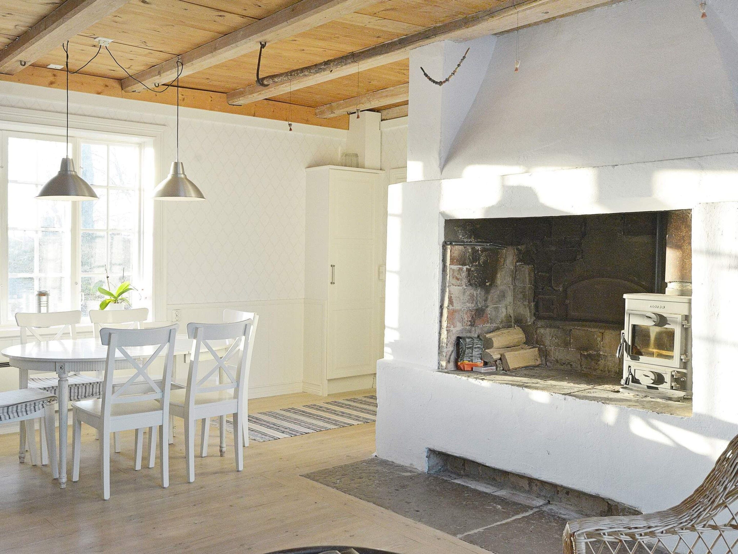 Habitació amb llar de foc, mobles blancs i sostre de fusta.
