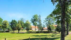A grassy park area with trees and a fence. - 6 Person Holiday Home in Hova (Hova)