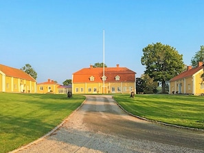 A large building with a central flagpole, surrounded by well-maintained lawns and smaller buildings. - 6 Person Holiday Home in Hova (Hova)
