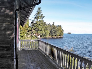 A wooden deck with a railing overlooking a body of water and a forested island. - 6 Person Holiday Home in Hova (Hova)