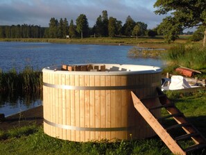 A wooden hot tub with a metal ladder, situated by a lake with a wooden dock. - 6 Person Holiday Home in Hova (Hova)