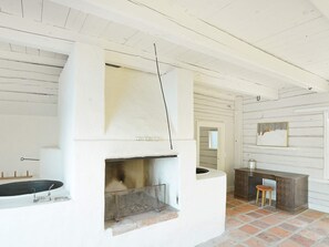Une pièce avec une cheminée, un banc en bois et un mur rustique.