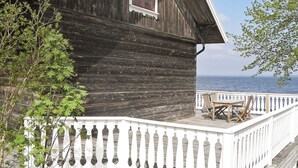 A wooden building with a white balcony and a view of the sea.