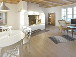 A spacious living area with a fireplace, white furniture, and a large window.
