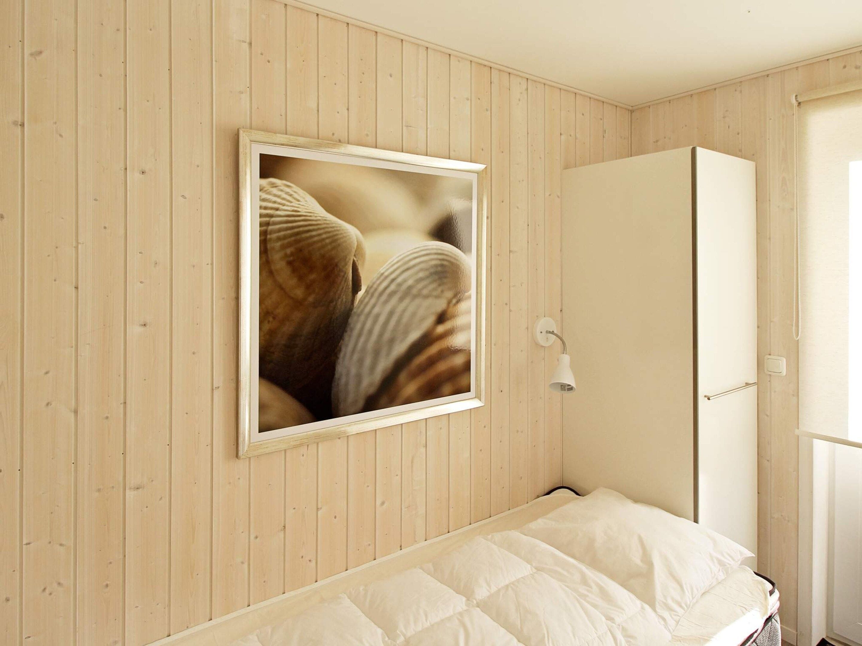 Une chambre à coucher avec un lit, une armoire et un tableau encadré au mur.