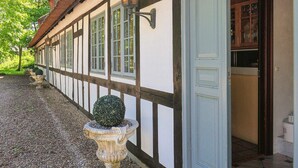 Ein traditionelles Fachwerkhäuschen mit einem Kiesweg und einer Kugelgestalt aus geschnittenen Pflanzen.