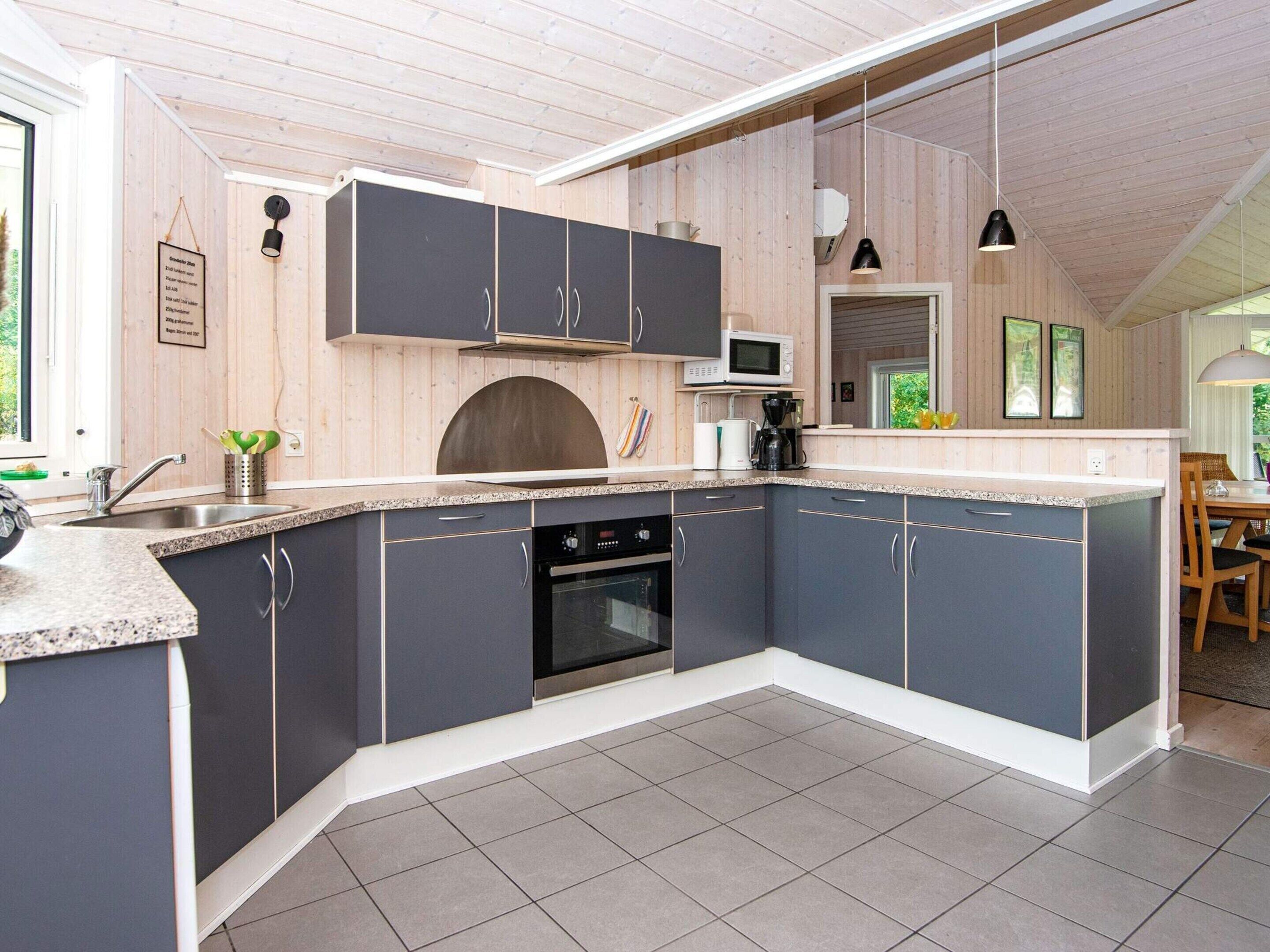 Une cuisine moderne avec des meubles de couleur sombre, un four à micro-ondes et un four encastré.