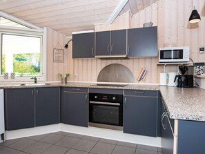 A modern kitchen with dark cabinets, a built-in oven, a microwave, and a coffee maker. - 4 Star Holiday Home in Glesborg (Glesborg)